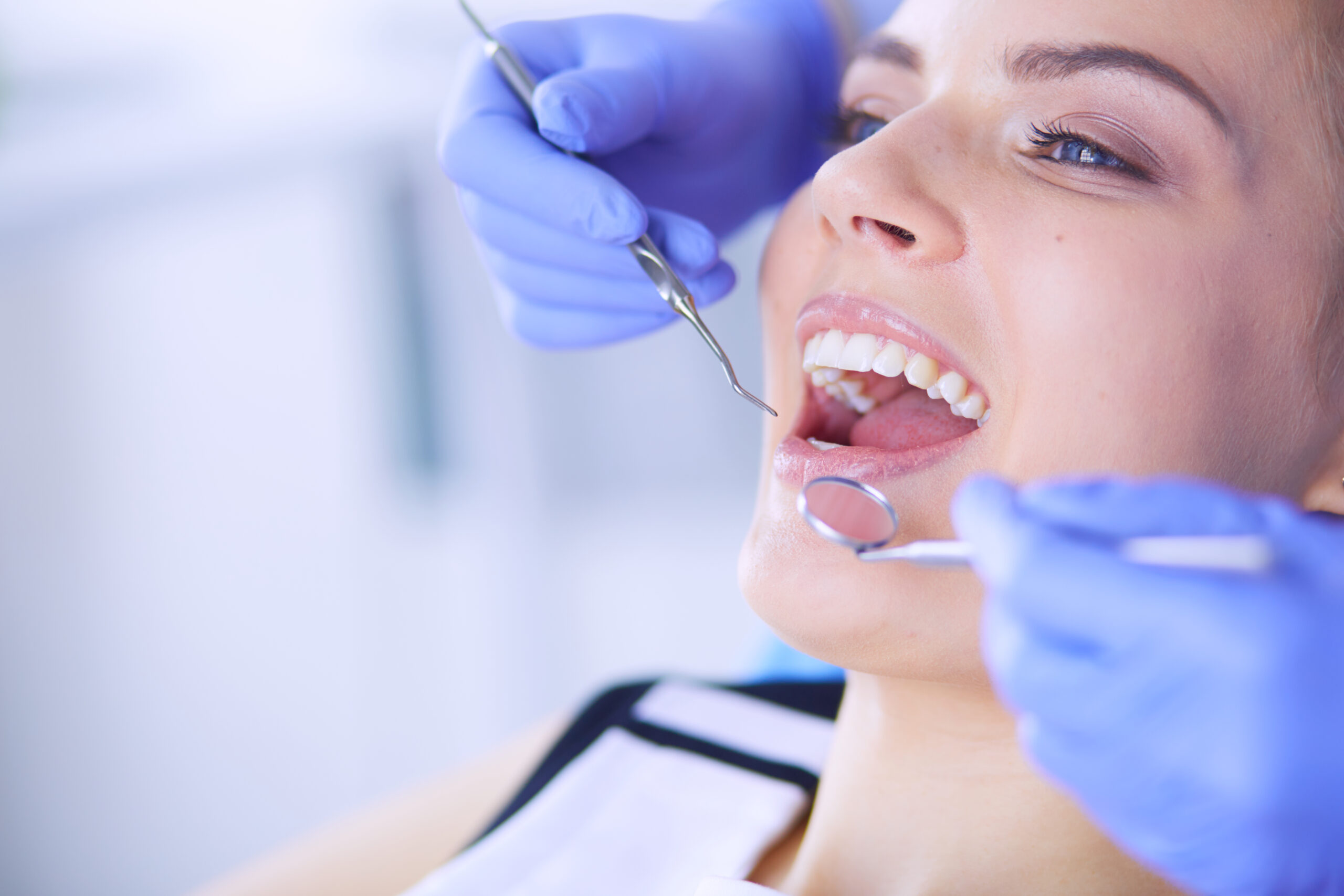 Young Female patient with open mouth examining dental inspection at dentist office