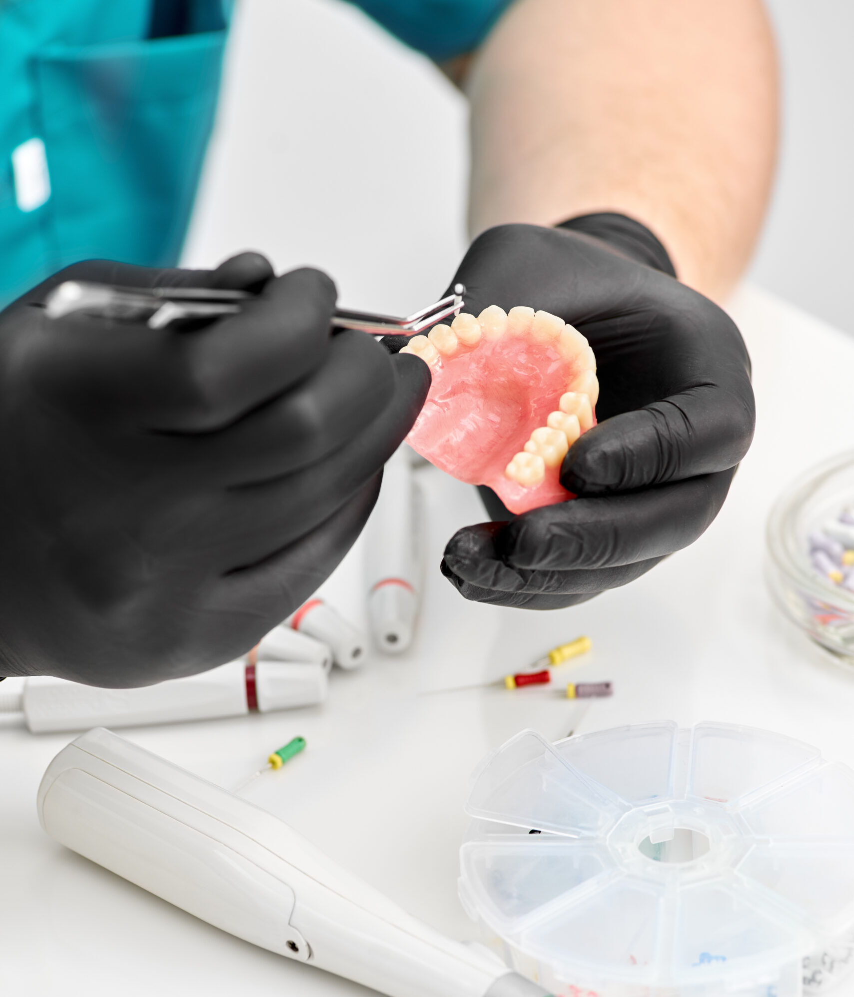 Orthodontist is working on cast of jaw. Orthodontics. Orthodontist makes a denture. Close up of the dentist's hands prosthesis, dentures, prosthetics work. Prosthetics hands while working on the denture, a study and a table with dental tools.